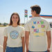Two people wearing t-shirts with colorful graphics and text, standing in a parking lot.
