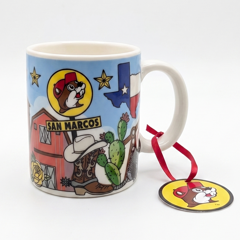A white ceramic mug featuring a colorful cartoon illustration of San Marcos from The Looney Tunes, with a red hanging ribbon and matching round tag on a white background.