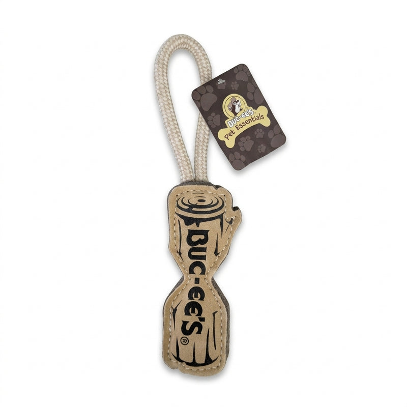 A Buc-ee's Pet Essentials dog toy shaped like a wooden log made of tan leather with "BUC-EE'S" text on the front, attached to an off-white braided rope loop handle.