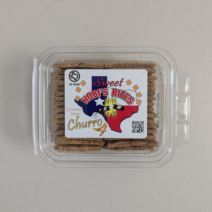 Cinnamon sugar churro crackers in a clear plastic clamshell container with a “Sweet Hobi’s Bites” Texas-themed label on a white background. Displayed on a gray neutral background.