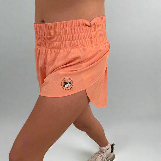 Side view of a woman in orange Buc-ee's performance shorts mid-stride