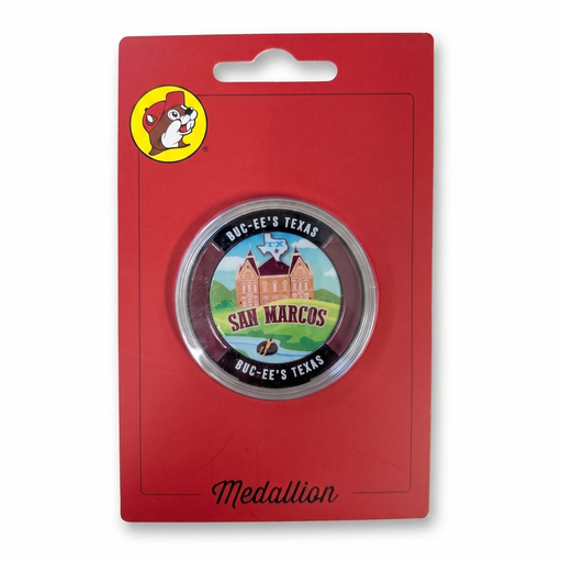 A circular San Marcos Buck-EE's Texas medallion pin, displayed on its original red blister card packaging with the Buck-EE's logo.