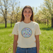 Person wearing a t-shirt with a colorful design in a grassy field