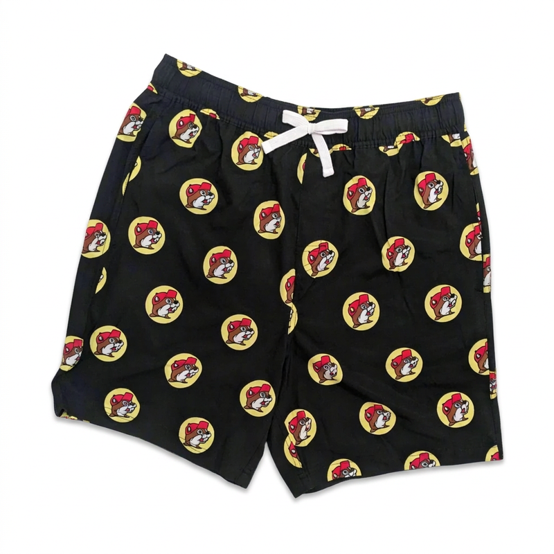 Buc-ee’s black logo swim trunks with all-over yellow beaver logo print, white drawstring, and elastic waist, front view