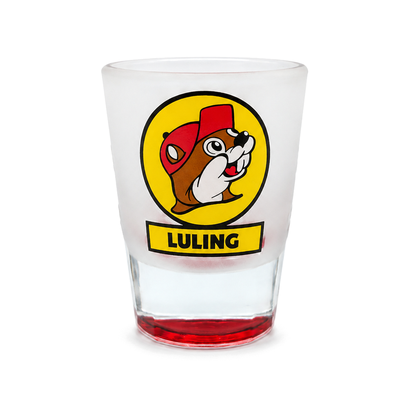 Buc-ee's Luling shot glass in frosted glass with the beaver logo in a yellow circle and a red-tinted clear base
