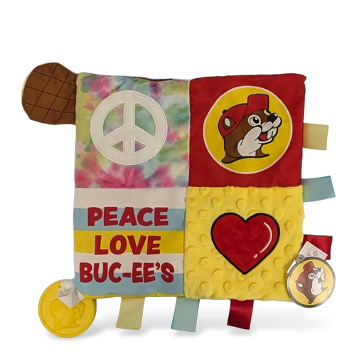 Buc-ee’s baby activity blanket with tie-dye, peace sign, and heart panels, ribbon tags, a beaver tail, and a yellow teether