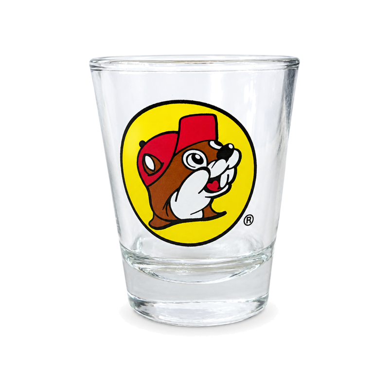 Buc-ee's clear glass shot glass with the beaver mascot logo in a yellow circle, a Texas road trip souvenir