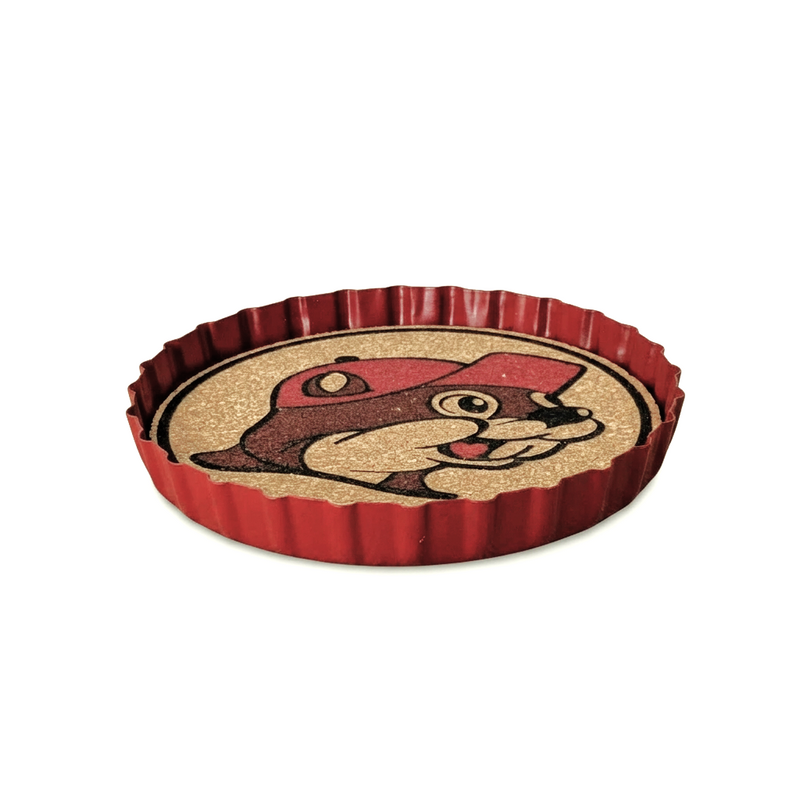 Buc-ee’s beaver bottle cap coaster in red metal with a crimped edge and cork center showing the mascot’s face