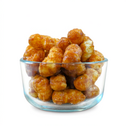 Buc-ee’s Beaver Nuggets Cinnamon Sweet puffs in a clear glass bowl, showing their glossy brown glaze up close