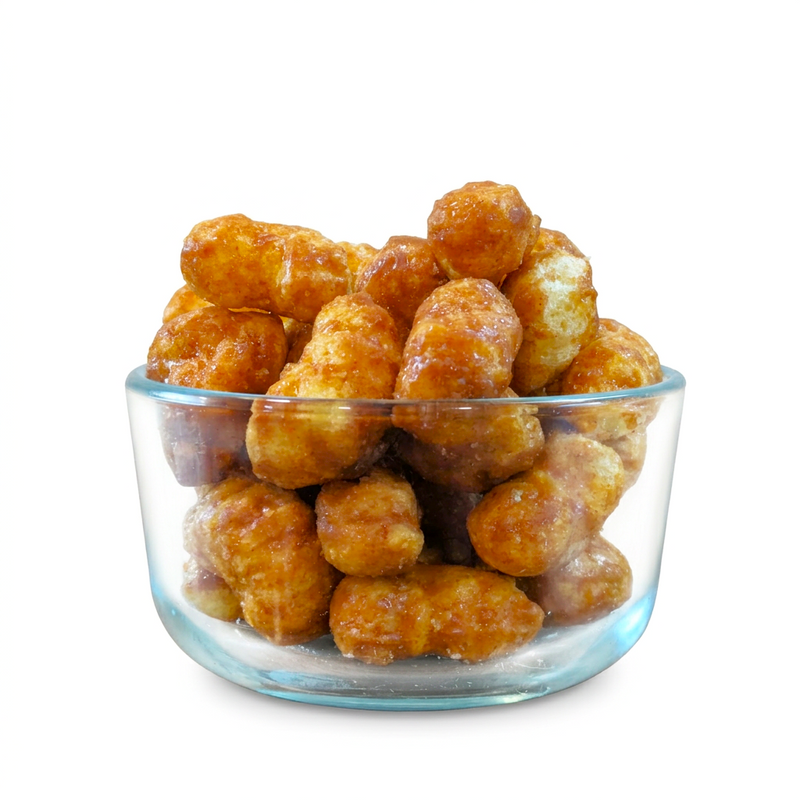 Buc-ee’s Beaver Nuggets Cinnamon Sweet puffs in a clear glass bowl, showing their glossy brown glaze up close