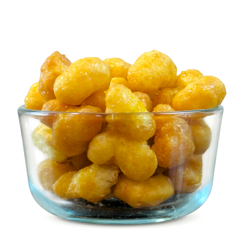 Buc-ee’s Beaver Nuggets puffs in a clear glass bowl, showing their light golden glaze and crunchy texture up close