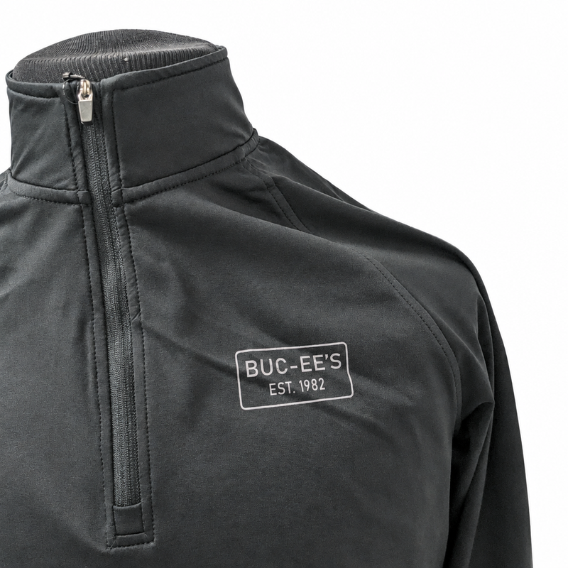 Buc-ee's black quarter-zip pullover chest detail with light gray EST. 1982 rectangle logo, metal zipper pull, and stand collar