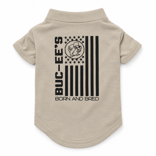 Back view of a tan pet t-shirt flat lay displaying a black US flag graphic with Buc-ee the Beaver, "BUC-EE'S" text, and "BORN AND BRED" printed at the bottom.