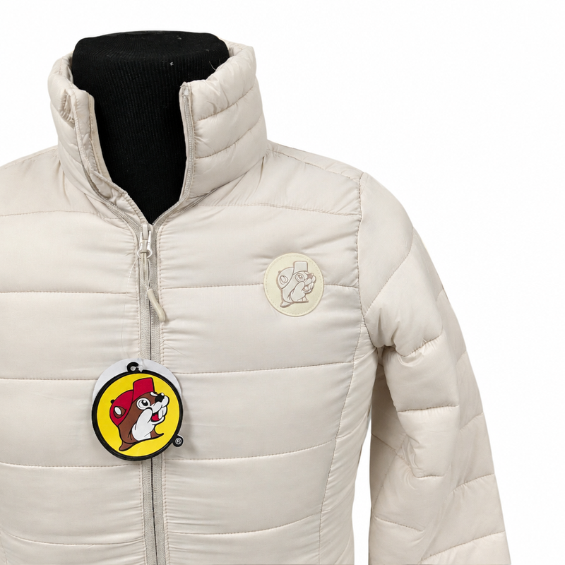 Close-up of the cream Buc-ee's puffer coat showing the tonal beaver logo patch, stand collar, and zipper pull detail