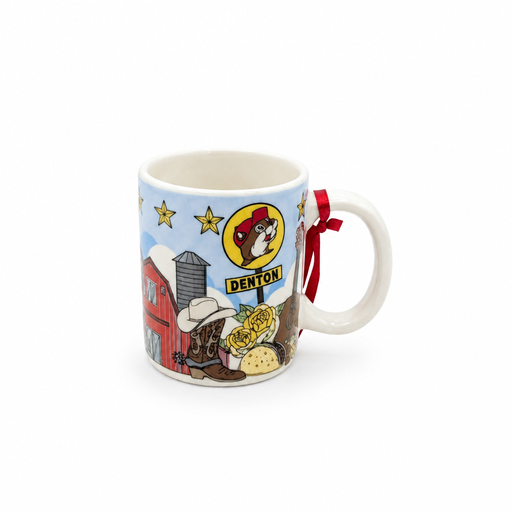 A white ceramic mini mug against a clean white background featuring a light blue sky wrapped in Texas-themed illustrations. The graphics include a red barn, a Texas longhorn steer, a taco, roses, a horseshoe, a Texas flag map outline, and a yellow Buc-ee's sign reading "DENTON". A small red hanging string is tied to the handle.