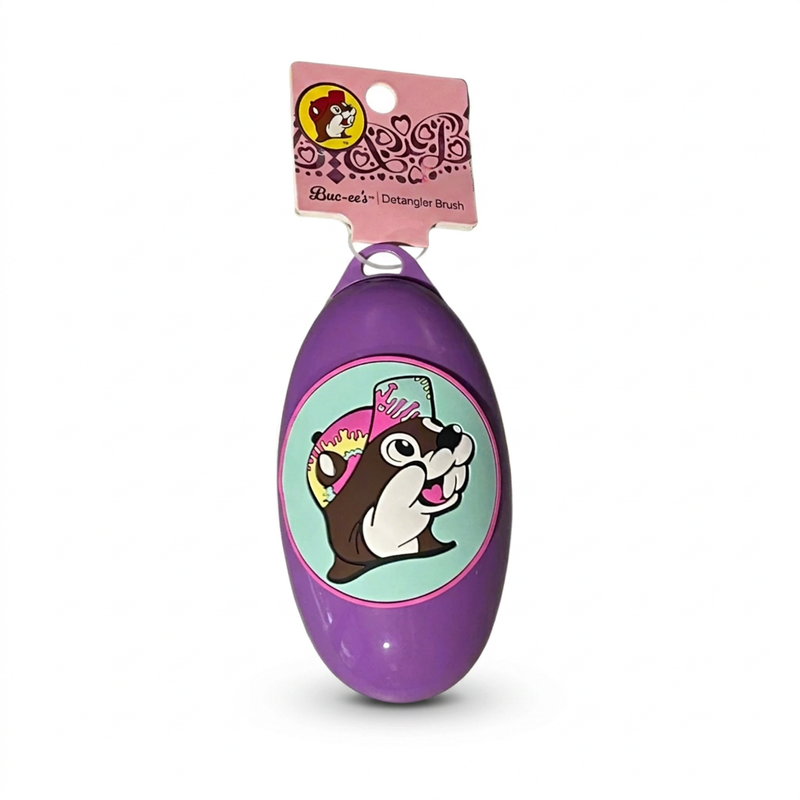 Buc-ee’s oval detangler brush in purple with the beaver in a pink tie-dye cap on an aqua circle