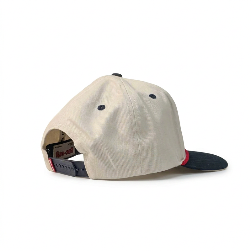 Buc-ee’s “Fresh Brisket on the Board” hat showing the cream side panels, navy eyelets, and navy snapback closure