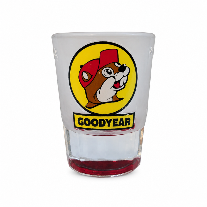 Buc-ee's Goodyear, AZ souvenir shot glass with frosted top, red-tinted base, and yellow beaver logo over GOODYEAR banner
