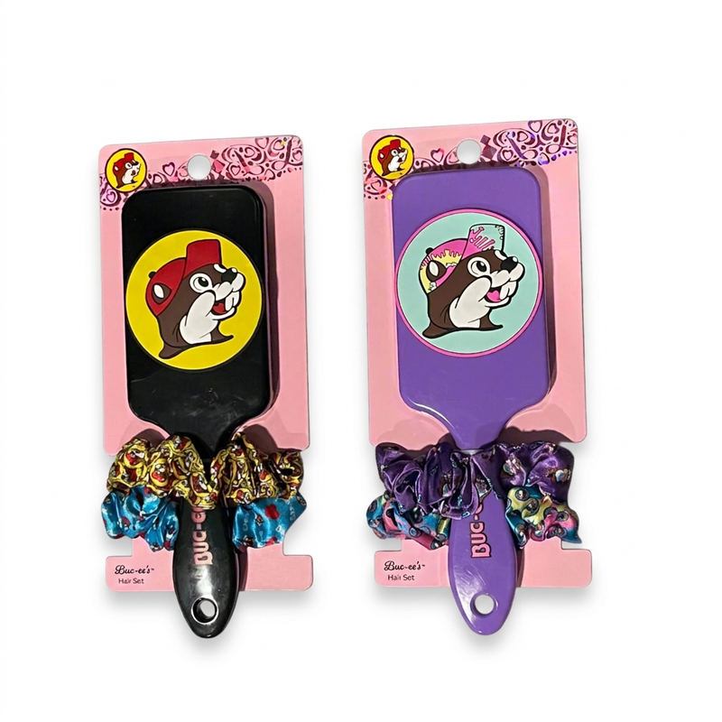Buc-ee’s hair sets in black and purple, each with a beaver logo paddle brush and printed scrunchies on a pink card