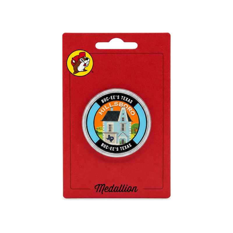 Buc-ee's Hillsboro medallion with a blue house and orange sky design in a clear capsule on red blister card packaging