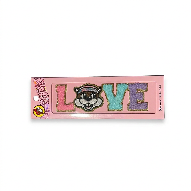 Buc-ee’s Love sticker patch in pastel chenille letters with gold glitter trim and a beaver face as the O, on a pink card