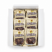 Top-down view of an open Buc-ee's OverBite Dark Chocolate Cookies & Cream box on a white background, showing the top layer of six individually wrapped cookies in speckled cream wrappers.
