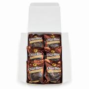 Top-down view of an open Buc-ee's OverBite Dark Chocolate Peanut Butter box on a white background, showing the top layer of six individually wrapped cookies in shiny bronze wrappers.
