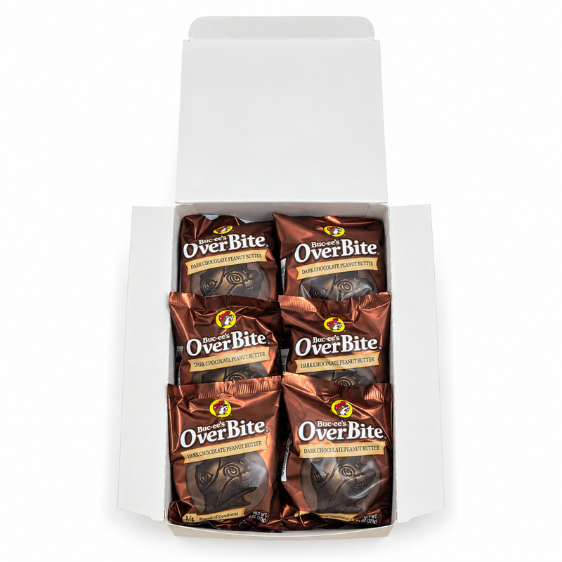 Top-down view of an open Buc-ee's OverBite Dark Chocolate Peanut Butter box on a white background, showing the top layer of six individually wrapped cookies in shiny bronze wrappers.
