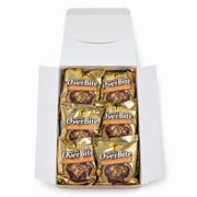 Top-down view of an open Buc-ee's OverBite Milk Chocolate Peanut Butter box on a white background, showing the top layer of six individually wrapped cookies in pale gold foil wrappers.
