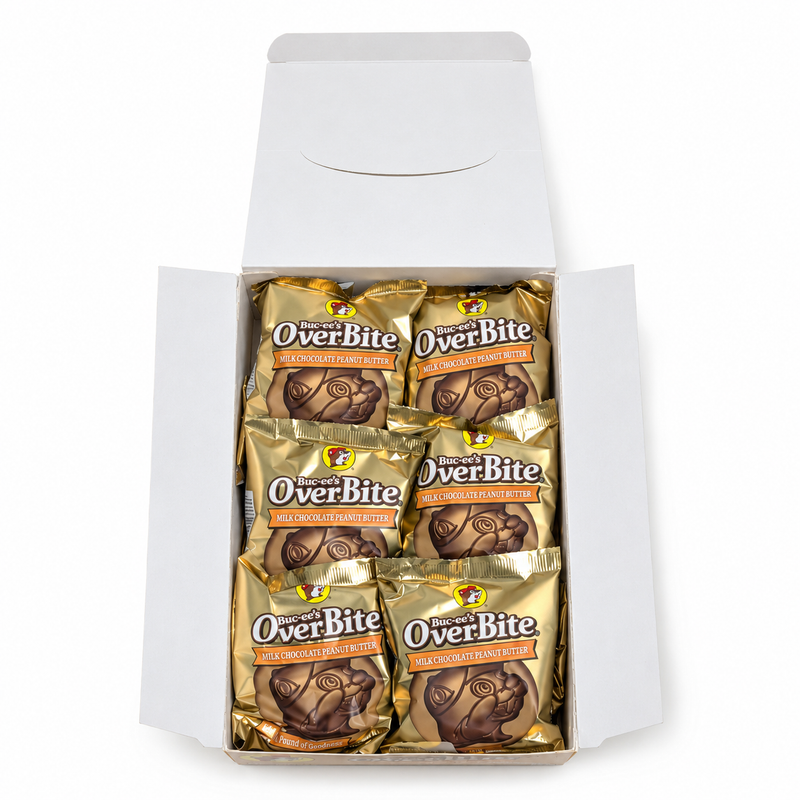 Top-down view of an open Buc-ee's OverBite Milk Chocolate Peanut Butter box on a white background, showing the top layer of six individually wrapped cookies in pale gold foil wrappers.
