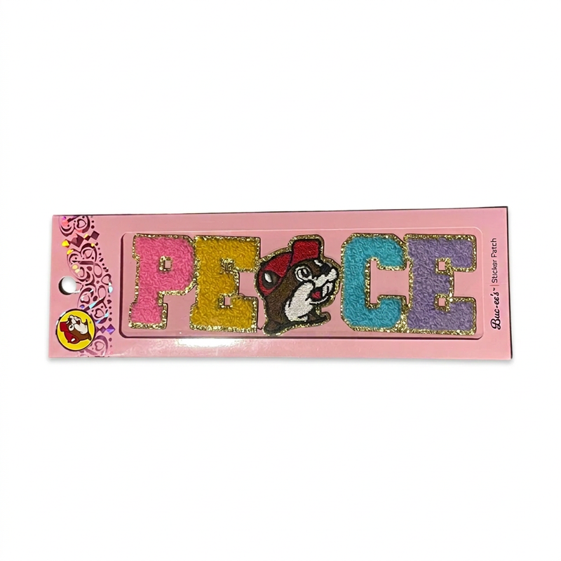 Buc-ee’s Peace sticker patch in bright chenille letters with gold glitter trim and a beaver as the A, on a pink card