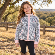 Girl on a ranch wearing the youth snow camo Buc-ee's fleece jacket