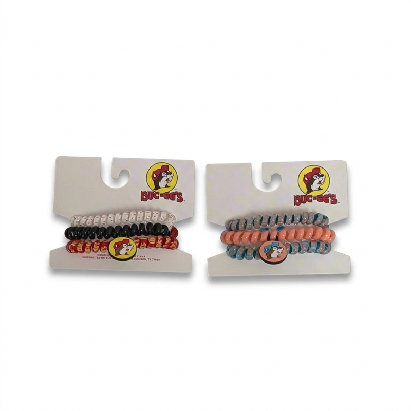 Buc-ee’s telephone cord hair ties in two 3-packs, one in white, black, and red and one in glitter blue and coral