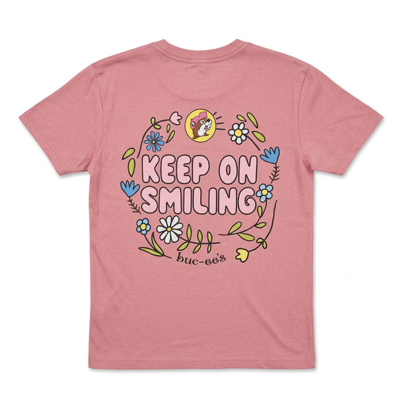 Back of Buc-ee’s Youth Keep on Smiling T-shirt in dusty pink with bubble lettering, floral wreath, and beaver logo