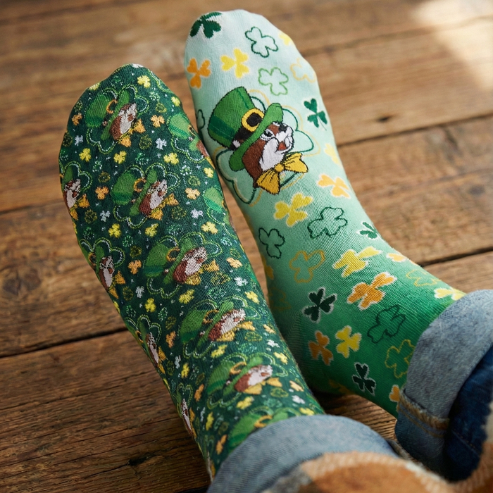 Green patterned socks with shamrocks and leprechauns on a wooden floor.