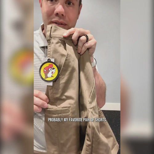 Buc-ee’s Caribou Fishing Twill Shorts review featuring tan-brown shorts with front slash pockets, a slim right-leg pocket, a Buc-ee’s logo tab on the back pocket, and men’s waist sizes 32 to 42.