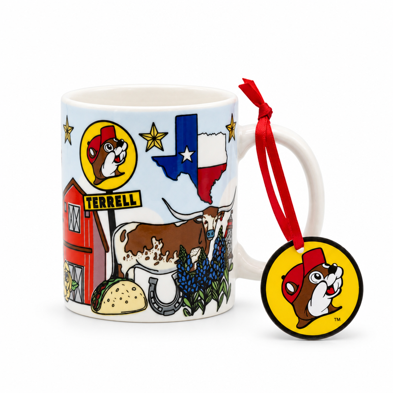 A mini white ceramic mug ornament against a plain white background featuring Texas-themed illustrations, including a Texas flag, a Longhorn steer, bluebonnets, a taco, and a red barn next to a Buc-ee's logo sign reading "TERRELL". A red ribbon tied to the handle holds a round, yellow Buc-ee's beaver head logo tag.